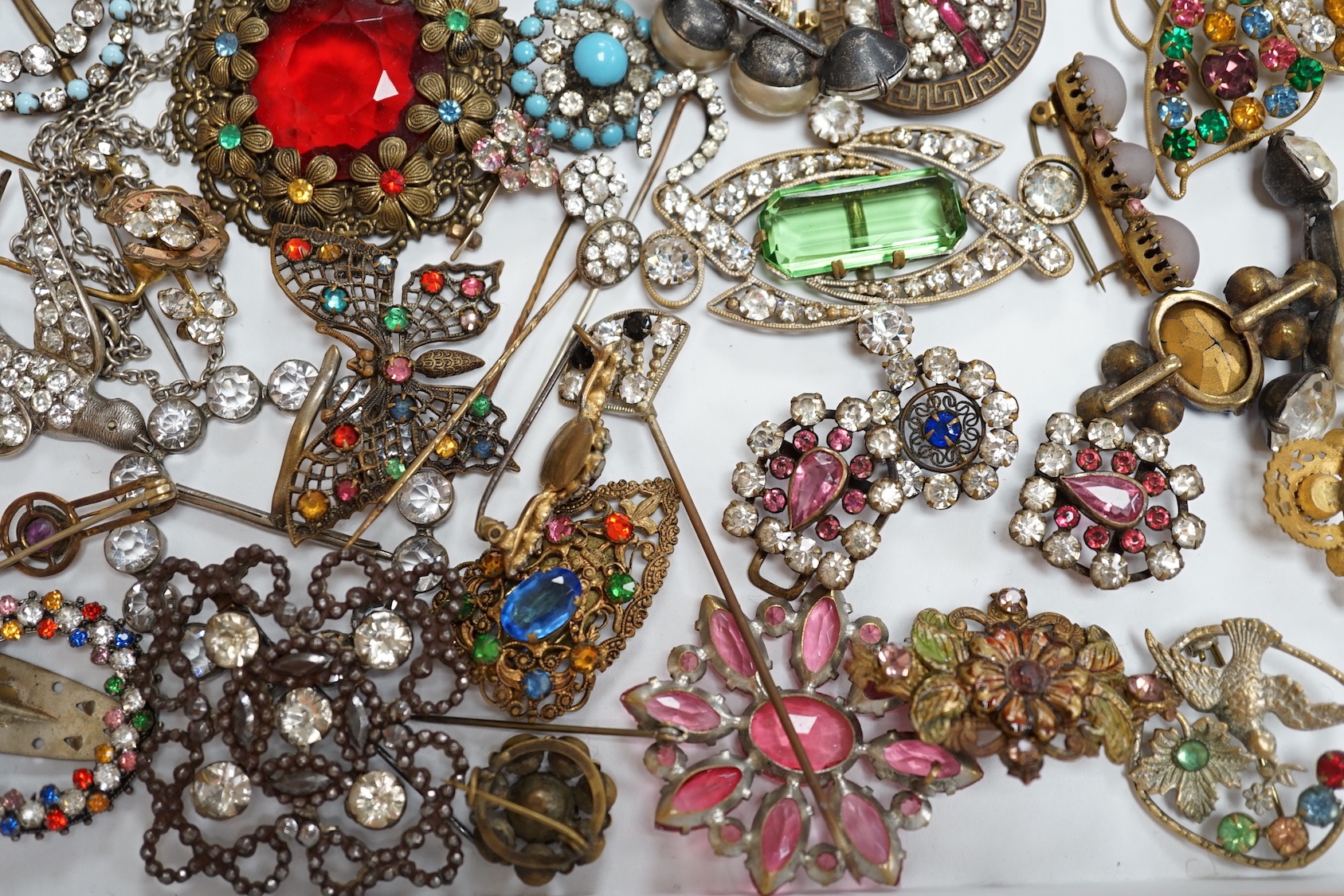 A quantity of assorted coloured and white paste jewellery, including brooches and buckles.